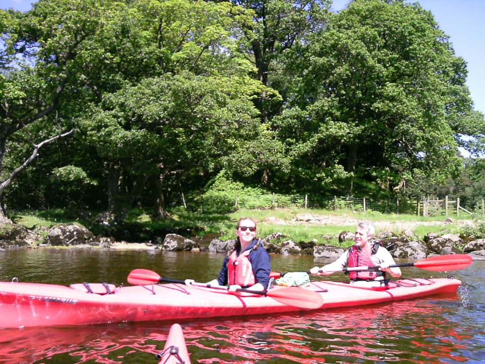 A couple paddling a kayak on the calm waters of Ullswater, surrounded by the stunning scenery of The Lake District.